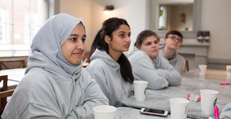 Young girls sitting at a row of desks