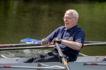 An older man rowing on a lake.