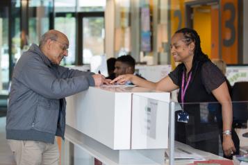 Receptionist helping a man to fill out a form